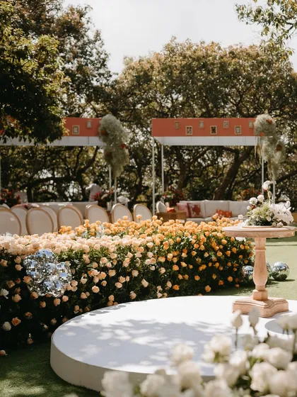 The central aisle of this garden ceremony was designed as a river of flowers, with dense beds of white, peach, and yellow roses creating a stunning ombré effect.