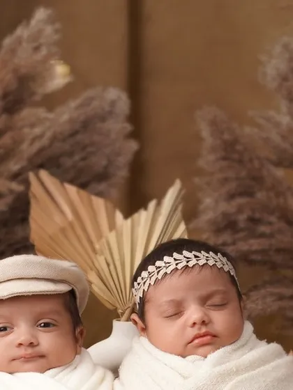 A sweet portrait of newborn twins nestled together. One is awake and looking at the camera while the other sleeps, perfectly capturing their individual personalities even at this early stage.