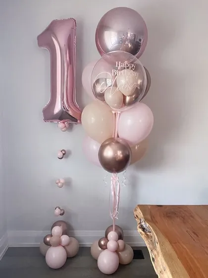 Celebrate a first birthday in style with this elegant balloon bunch. The arrangement includes a large number "1" foil, a personalized bubble balloon, and latex balloons in a soft, neutral palette.