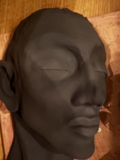 The same sculpture after being coated with a dark slip. This step adds depth and prepares the surface for further decoration or firing.