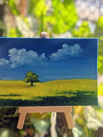 This peaceful field scene on its easel is ready to bring a bit of calm to any space. It’s a reminder of the simple beauty found in nature, captured with oil paints.