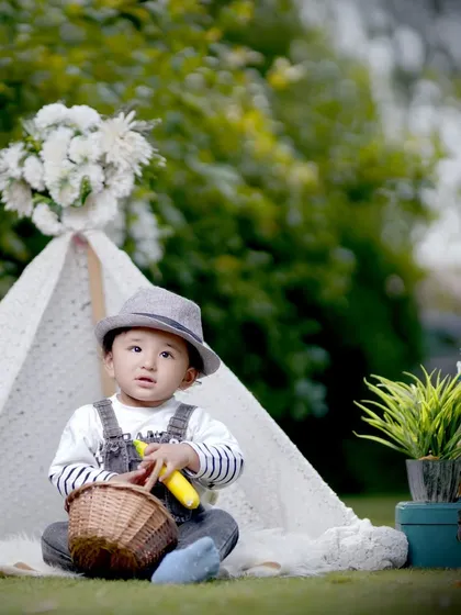 A professionally styled outdoor photoshoot for a toddler, featuring a lace teepee and rustic props in a green park setting. This is a great example of our themed kids' portrait sessions available in the Noida area.