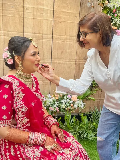 A behind-the-scenes moment of me applying the final touches to the bride's lipstick. This interaction is part of the calm and collaborative process I create for my brides.