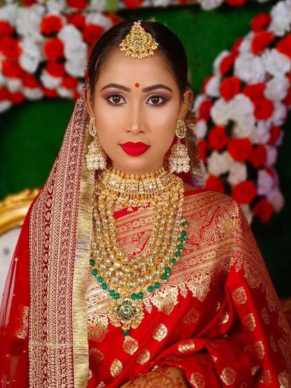 A direct portrait of the Bengali bride, showcasing the iconic red bindi and intricate gold jewellery.