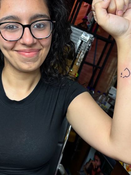 A tiny heart with a smiley face. Minimalist tattoos like this are perfect for a first-time tattoo experience.