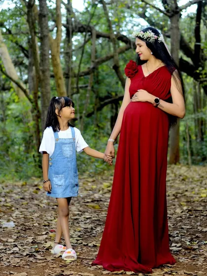 A heartwarming moment between a mother and her child, anticipating the new arrival. This red maternity gown is perfect for family-focused maternity shoots.