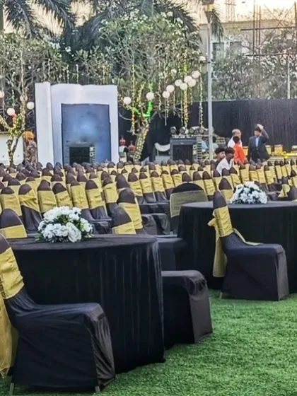 A large-scale outdoor event setup on a lawn, with rows of chairs covered in black and yellow fabric, ready for a corporate event or concert.