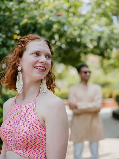 A playful shot of the couple. The bride's modern pink halter top and the groom's relaxed kurta create a perfect look for a casual, sunny wedding event.
