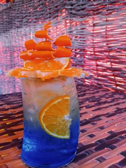 Our mocktails are as creative as our cocktails. This layered blue and orange drink is garnished with an intricate boat made from orange slices, perfect for a themed party.
