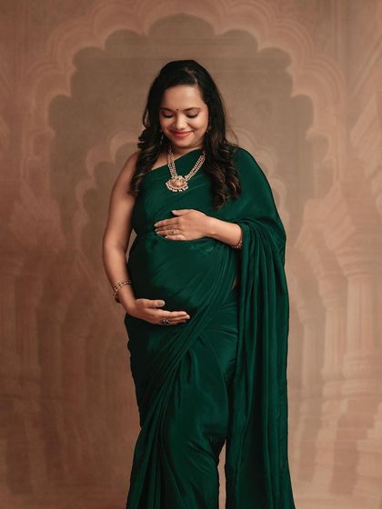 A serene moment of a mom-to-be looking down at her bump. The elegant drape of the green saree is beautifully captured in this shot.