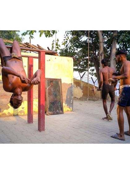 A young man performs an exercise at an outdoor gym by the river in Delhi. This image captures the raw, physical culture of traditional Indian wrestling and bodybuilding (Kushti).