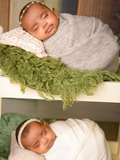 A close-up of the twin girls in their bunk bed, one in a grey swaddle and the other in white, both sleeping peacefully.