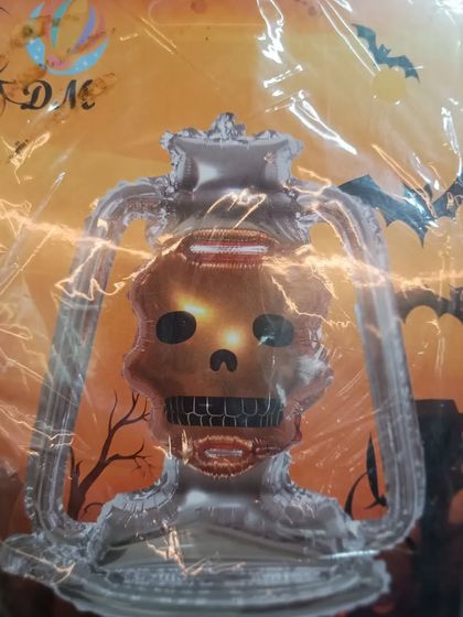 A spooky skull lantern foil balloon. This decoration looks like an old lantern but with a creepy skull face, adding a great touch to your Halloween decor.