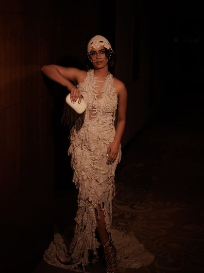 A full-length shot showcasing the complete avant-garde look for Vogue India. The moody lighting and dramatic pose highlight how the makeup and hair integrate with the textured gown to create a cohesive editorial statement.