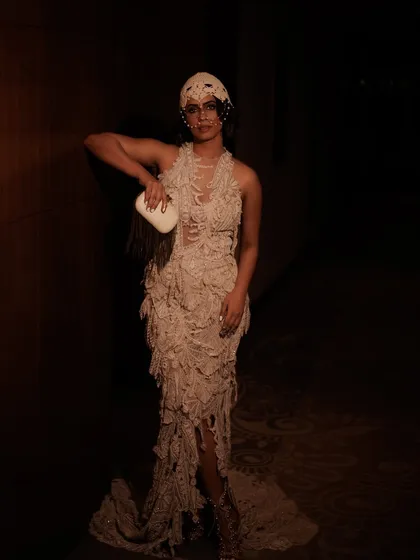 A full-length shot showcasing the complete avant-garde look for Vogue India. The moody lighting and dramatic pose highlight how the makeup and hair integrate with the textured gown to create a cohesive editorial statement.