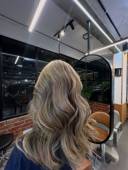 A view in the mirror of the finished ash blonde balayage, showing the dimension and texture of the style.