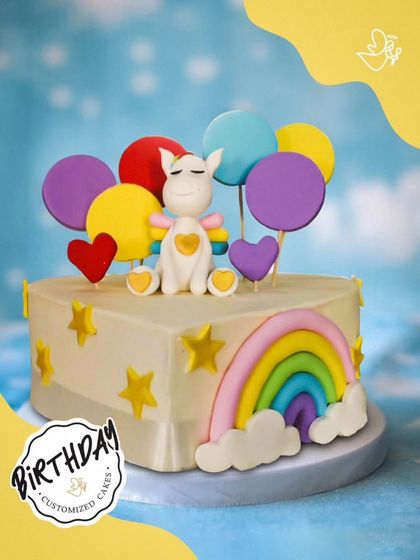 A heart-shaped unicorn and rainbow cake. This unique design is full of color and love, featuring a cute unicorn surrounded by balloons, stars, and a vibrant rainbow.