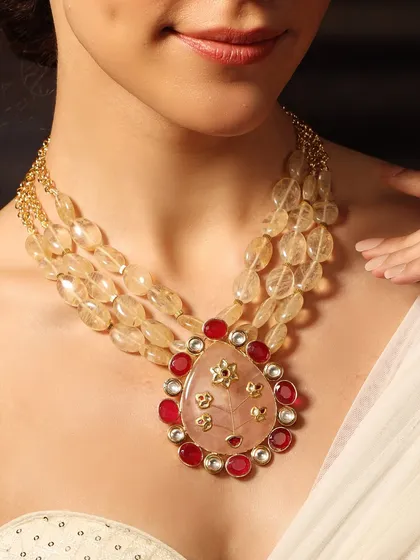 A bold and beautiful pendant necklace, featuring a large pink central stone surrounded by rubies, strung on a multi-strand beaded chain.