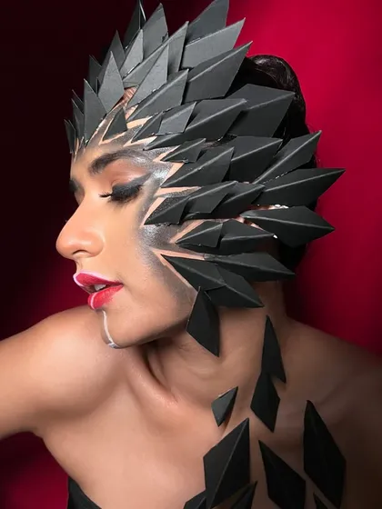A side profile of the fantasy look, showcasing the intricate, spiky headpiece and the sharp, graphic makeup.