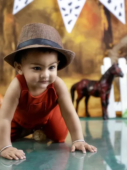 On the crawl in his cowboy gear. The farm-themed background with a red barn door and white picket fence is one of my most popular sets.