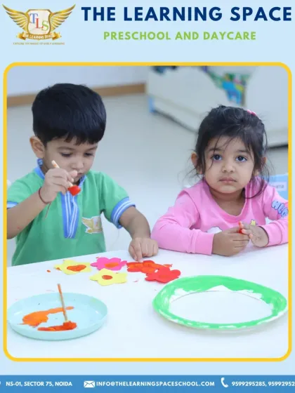 Two children deeply engaged in painting flowers. Activities like this help develop fine motor control and color recognition in a calm and focused environment.