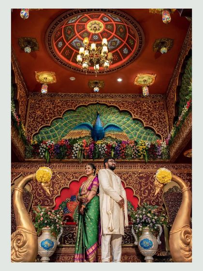 A stunning portrait of the couple against a backdrop of a peacock mural and floral decorations, highlighting the grandeur of the event.