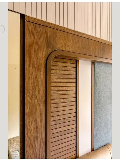 A detail of a headboard, showing the combination of wood, louvers, and fabric.