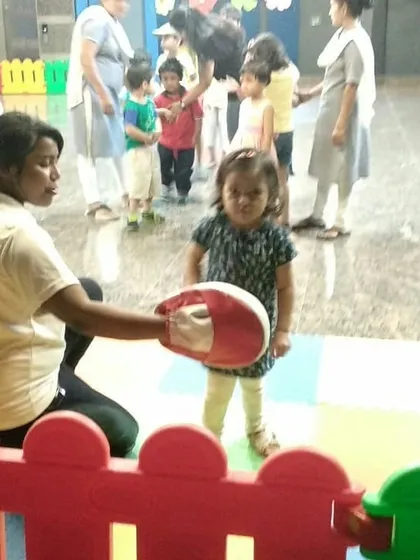 Even the tiniest tots can learn to be strong. A young child gets her first introduction to boxing gloves and pads at a playschool summer camp.