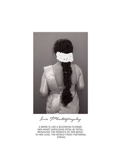 A simple and elegant black and white portrait from behind, showcasing the bride's traditional hairstyle with fresh flowers. It's a timeless and artistic shot.