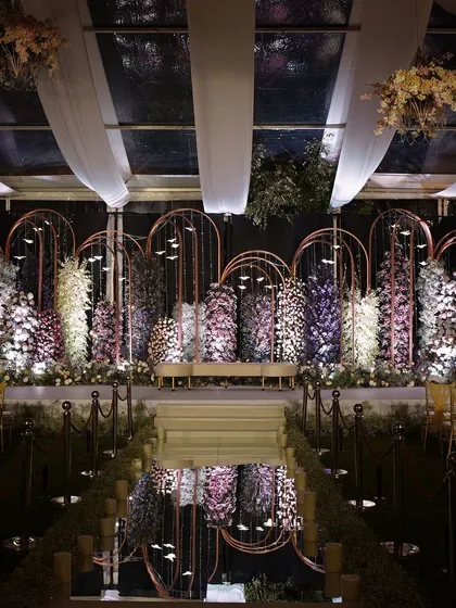 This modern stage design uses reflective surfaces and clean, metallic arches to create a chic and contemporary look. The symmetrical arrangement and dramatic lighting are perfect for a stylish cocktail party, product launch, or awards night.