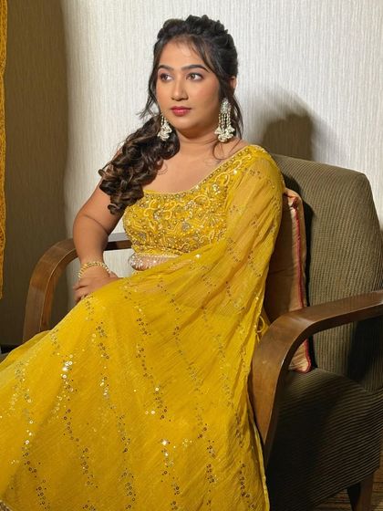 A seated portrait of the bride, looking thoughtful and serene. The side-swept hairstyle and soft makeup create a romantic and modern Haldi look.