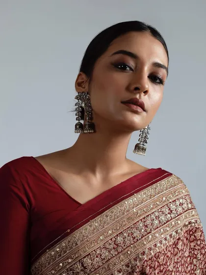 This is a royal inspired look from a professional photoshoot, featuring dramatic smokey eyes and a perfectly blended, matte base. The hair is styled in a sleek, low bun to complete the regal and powerful aesthetic.
