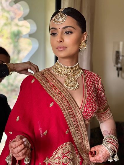 Final adjustments being made to the dupatta. The bride looks serene and ready for her big moment.