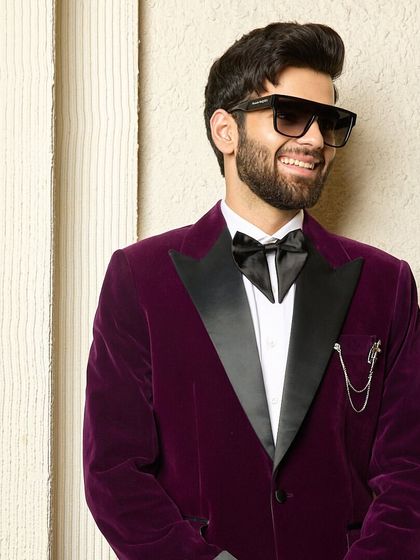 A smiling client wears the wine velvet tuxedo, radiating confidence and charm. This look is perfect for making a memorable entrance at any festive or formal gathering.