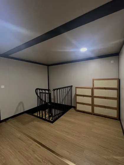 The internal staircase in our two-story container home. The black metal railing adds a touch of industrial chic, while the wooden stairs maintain a warm, residential feel.