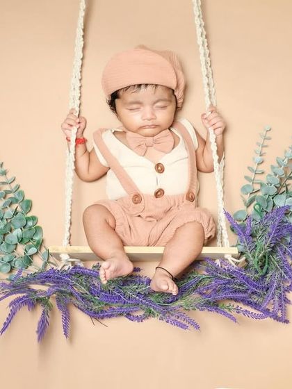 This little boy looks so dapper in his outfit, sleeping on a swing decorated with lavender. A beautiful and serene portrait.