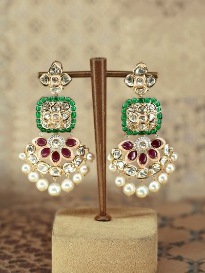 These statement earrings are a celebration in themselves. They feature vibrant emerald and ruby accents, shimmering polki, and delicate pearls for a perfect blend of tradition and glamour.