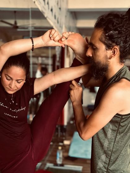 In my teacher training course, I focus on hands-on adjustments. Here, I am guiding a student into a deep standing split against the wall.