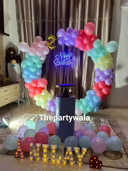 A simple and sweet pastel rainbow heart-shaped balloon arch. The light-up name and single pedestal create a minimalist yet beautiful setup.