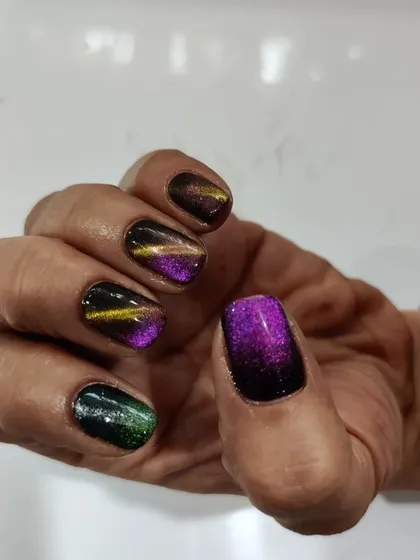 Magnetic cat-eye polish on natural nails, showing a beautiful mix of purple, gold, and green tones.
