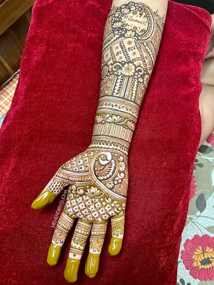 A single hand from Ruchita's engagement mehendi, featuring a beautiful peacock and the groom's name, 'Sumeet', elegantly written on the forearm.
