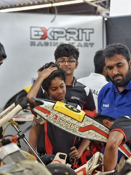 A young driver receives guidance in the pits. We foster a learning environment where experienced mechanics and coaches support emerging talent.