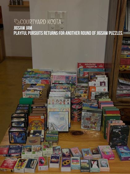 A table laden with a huge variety of jigsaw puzzles, ready for our Jigsaw Jam event. We ensure there's a puzzle for every interest and skill level.