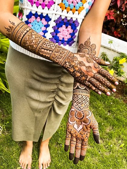 A full-length view showcasing the complete bridal henna design, from the detailed palms to the patterned forearms.