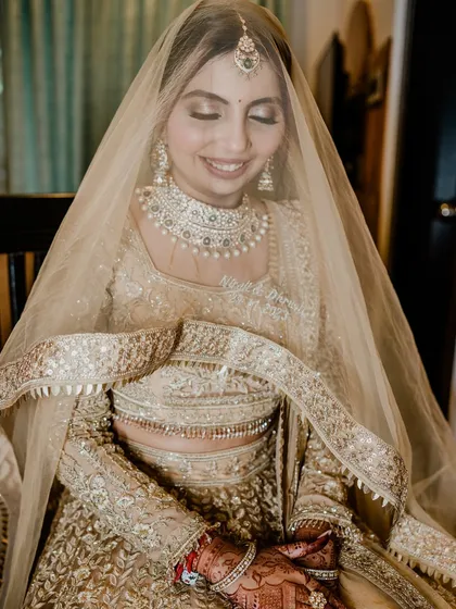 A serene portrait of the bride. The soft focus and her gentle smile highlight the ethereal quality of her all-gold bridal look.
