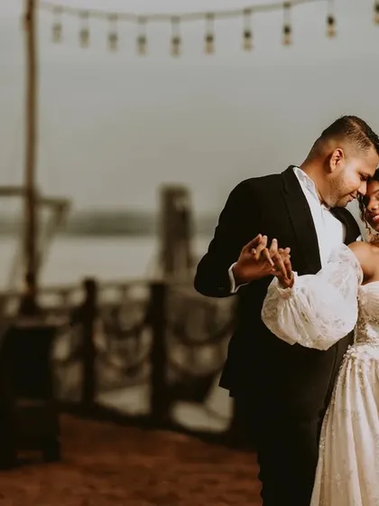 A moody, romantic portrait taken on a pier at dusk. The soft focus and warm tones create an intimate, film-like quality, perfect for capturing a quiet dance.