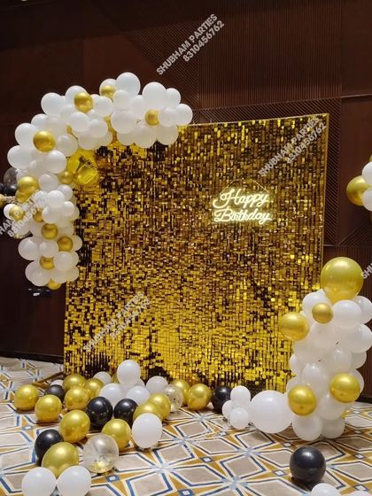 A gold sequin panel with a partial balloon arch, offering a different style for a chic birthday setup.