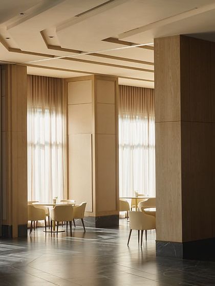 The grand pillars and high ceilings of the banquet hall at Rustomjee Elements. The design uses a combination of wooden, mirror, and wallpaper panels to add texture and sophistication to the large, open space.