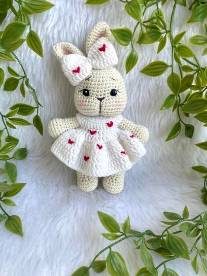 This sweet bunny is dressed in a white frock adorned with little red hearts. The matching bow on her ear makes her extra cute. A perfect gift for Valentine's Day or for someone you love.