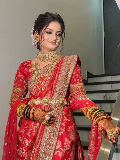 A full-length portrait of the bride on a staircase, showing off her red Nauvari and traditional jewellery.